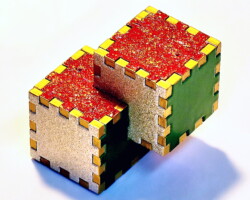 A Relativity Box with the sides painted 3 different colors and golden fingers.